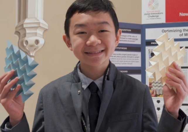 Miles Wu displaying two origami sheets