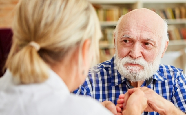 elderly man with a blank expression, looking at a younger woman