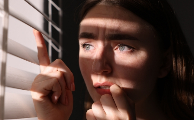 woman looking through the blinds