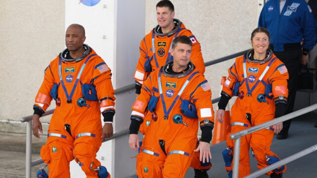 Four NASA astronauts walking out of a building 