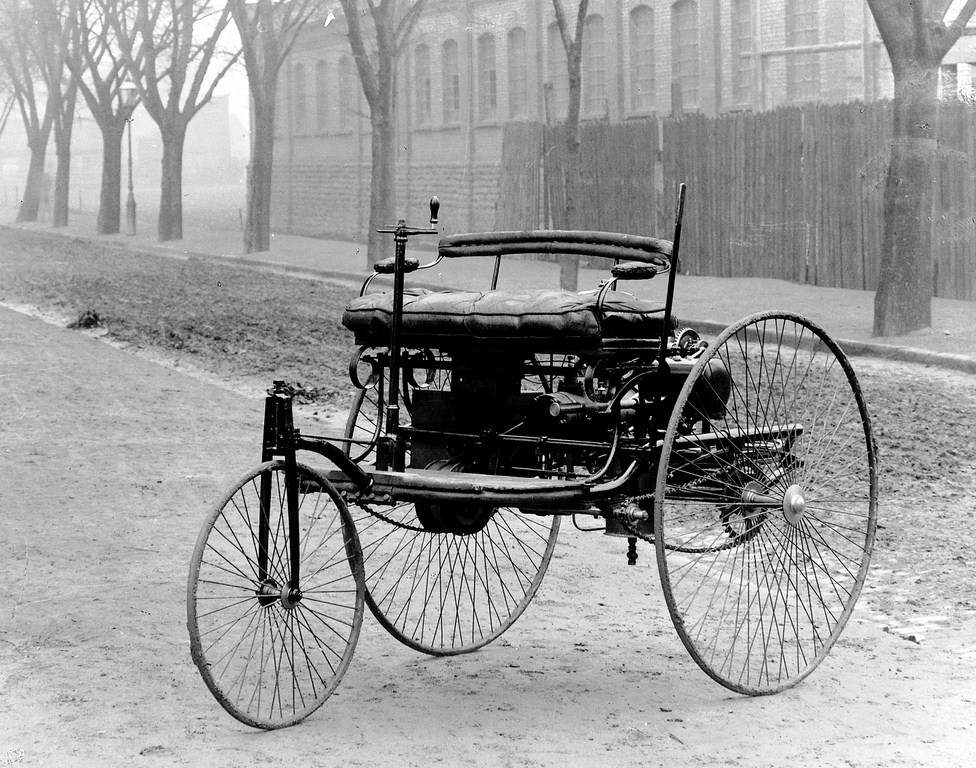 black and white photo of the world's first car - it's a bit like a carriage with very large spoked wheels