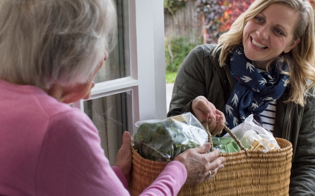younger woman giving an older woman some groceries