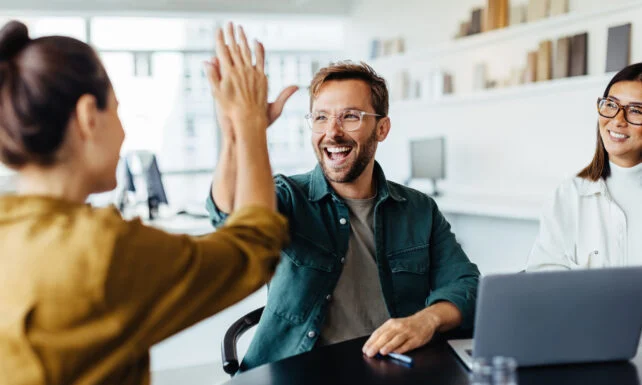 Two people giving each other a high five in a meeting