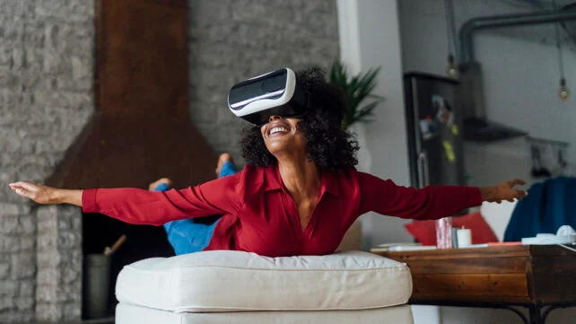 Woman lying on seating furniture, wearing VR goggles