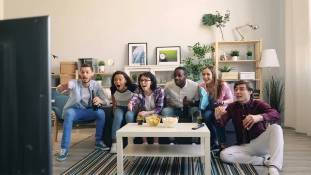 A group of adults on a couch watching TV