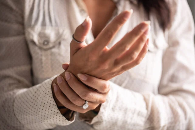 women holding onto her other hand like she's in pain